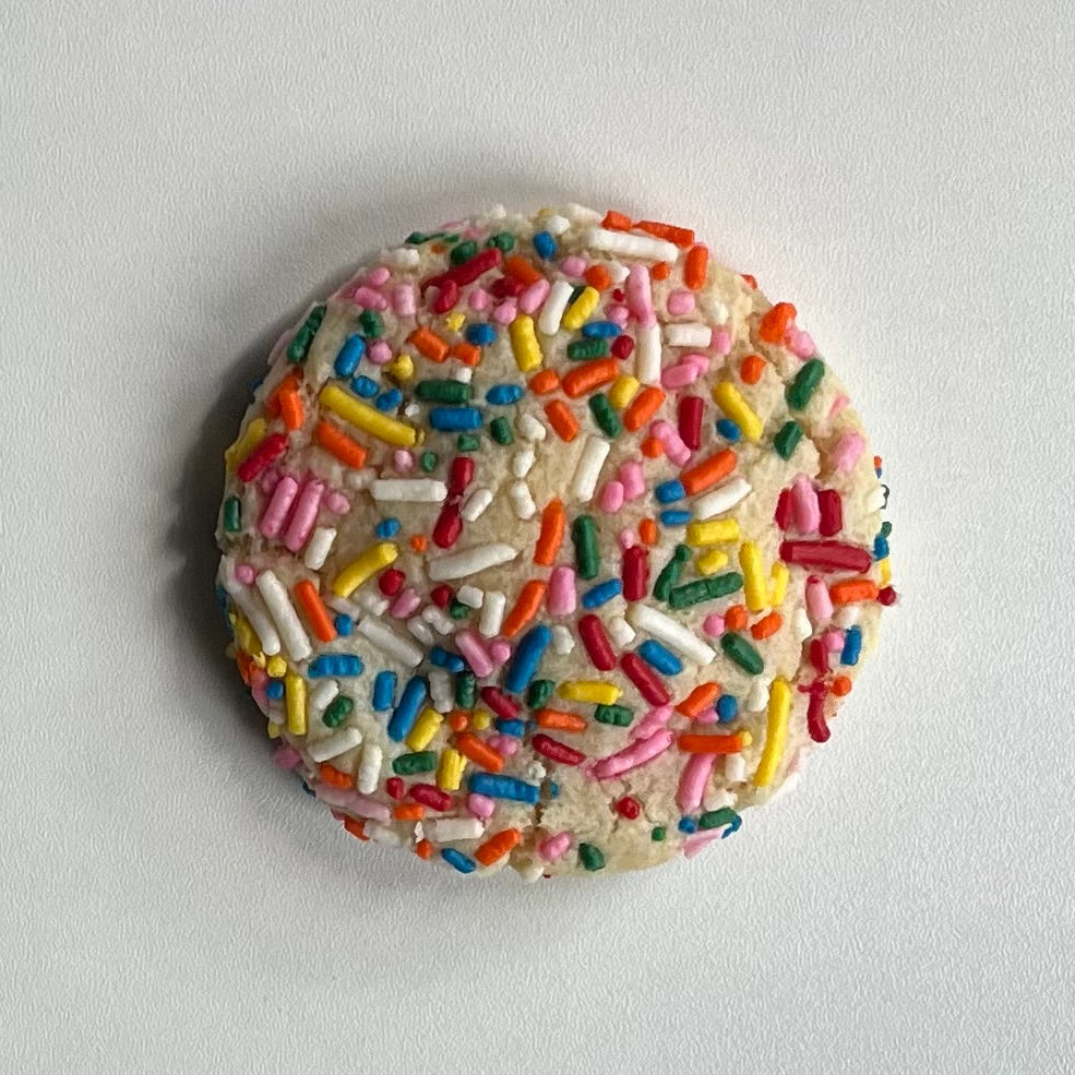 Cookie with colorful sprinkles on a light gray background